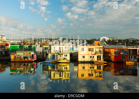 Case galleggianti al Fisherman's Wharf marina all alba con puffy nuvole riflettono in acqua-Victoria, British Columbia, Canada. Foto Stock