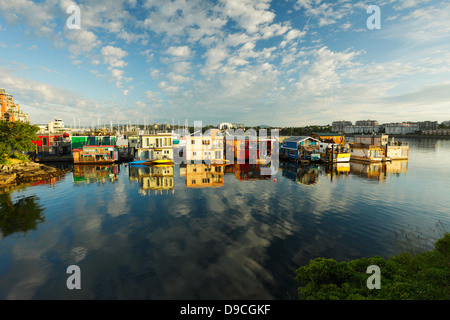 Case galleggianti al Fisherman's Wharf marina all alba con puffy nuvole riflettono in acqua-Victoria, British Columbia, Canada. Foto Stock