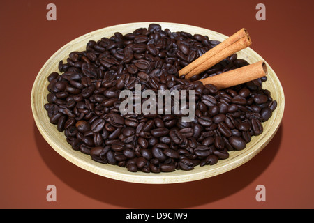 I chicchi di caffè con bastoncini di cannella in una ciotola Foto Stock