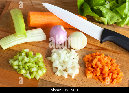 Coltello in ceramica con il soffritto sul tagliere di legno Foto Stock