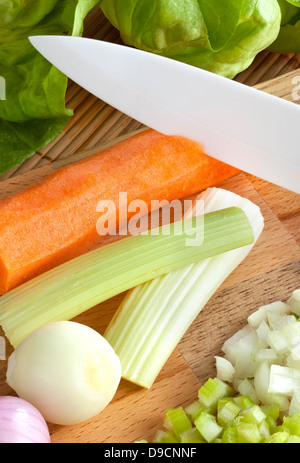 Coltello in ceramica con il soffritto sul tagliere di legno Foto Stock