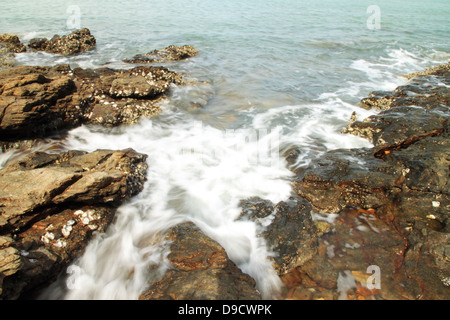 Le onde del mare di colpire round rocce e schizzi Foto Stock