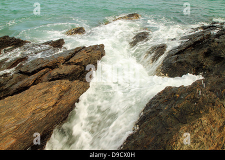 Le onde del mare di colpire round rocce e schizzi Foto Stock