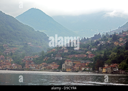 Le montagne si elevano al di sopra di villaggi lungo le rive del lago di Como in Italia settentrionale Foto Stock