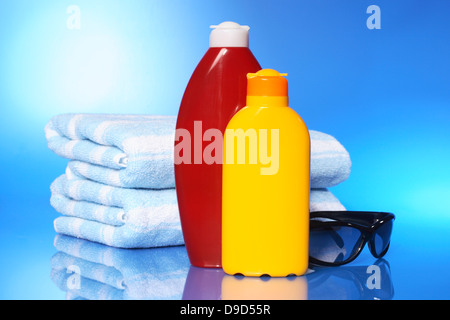 Teli da Bagno con latte solare e occhiali da sole Foto Stock