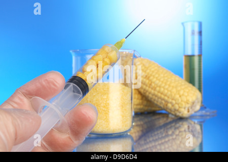 Mano con una siringa, la tazza di misura e di granturco Foto Stock