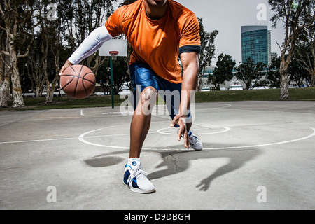 Giovane uomo giocare a basket sulla corte, close up Foto Stock