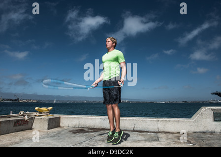 Giovane uomo con corda da salto sul molo Foto Stock