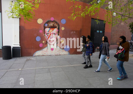 Brixton, Londra: 18 giugno 2013 - un murale di iconico musicista e cantante David Bowie è apparso sulla parete del Morleys department store di Brixton, Lambeth, nel sud di Londra. La faccia di Bowie è originato (dall artista James Cochran, aka Jimmy C) dal coperchio del suo 1973 album Aladdin Sane all'altezza dei suoi anni settanta fama. L'icona del pop ha vissuto a 40 Stansfield Road, Brixton, dalla sua nascita nel 1947 fino al 1953. Questo coperchio è apparso in Rolling Stone la lista dei 500 migliori album di tutti i tempi, rendendo #277. Credito: Richard Baker / Alamy Live News Foto Stock