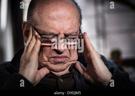 L'uomo anziano con gli occhi chiusi, indossando occhiali, cercando sottolineato Foto Stock