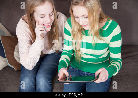 Ragazze seduti sul divano guardando a tavoletta digitale Foto Stock