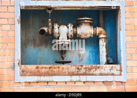 Tubi di ruggine rossa all'interno di un muro di mattoni Foto Stock