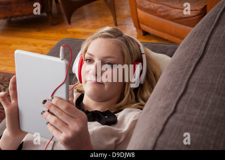 Ragazza distesa sul divano con tavoletta digitale Foto Stock