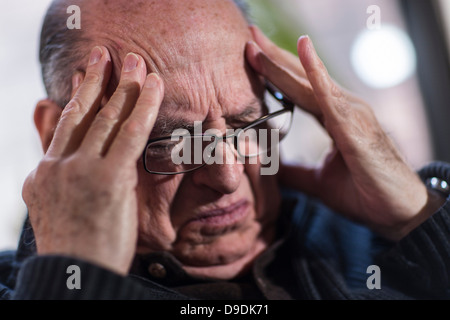 L'uomo anziano con gli occhi chiusi, indossando occhiali, cercando sottolineato Foto Stock