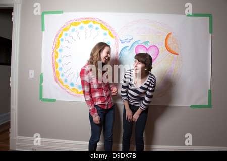 Le ragazze in piedi nella parte anteriore del murale di ridere Foto Stock