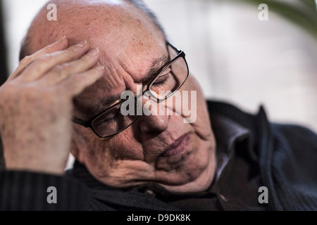 L'uomo anziano con gli occhi chiusi, indossando occhiali, cercando sottolineato Foto Stock