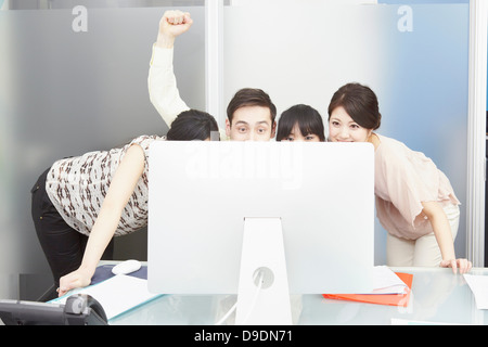 I colleghi guardando il monitor di un computer, l'uomo la punzonatura l'aria Foto Stock