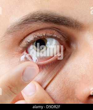 Primo piano di un uomo verde dell'occhio durante l'inserimento di un correttivo Foto Stock