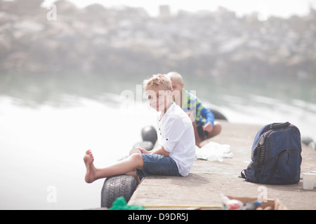 Due giovani ragazzi seduti sul molo pesca Foto Stock