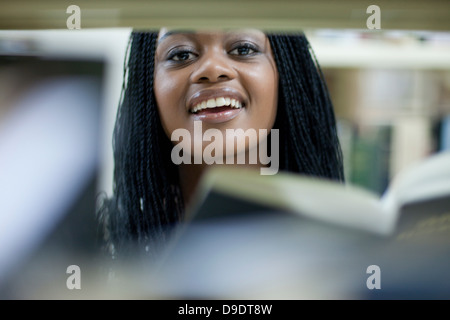 Studentessa del peering tra libri Foto Stock