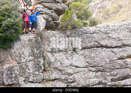 Mountain bike giovane guardando fuori dalla formazione di roccia Foto Stock