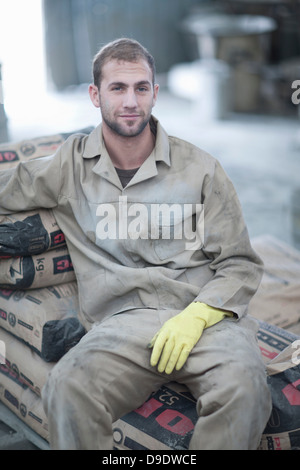 Uomo seduto sulla pila di sacchi di cemento Foto Stock