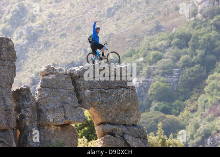 Giovane uomo su mountain bike permanente sulla formazione di roccia Foto Stock