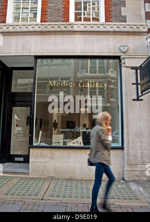 Femmina su telefono cellulare a camminare lungo la galleria dei Medici su Cork Street,una delle più famose strade per le gallerie d'arte a Londra Foto Stock