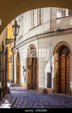 Vista attraverso un arco ad un piccolo vialetto in ciottoli nel quartiere del centro storico di Praga, Praha, Repubblica Ceca; Česká Republika. Foto Stock