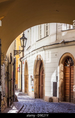 Vista attraverso un arco ad un piccolo vialetto in ciottoli nel quartiere del centro storico di Praga, Praha, Repubblica Ceca; Česká Republika. Foto Stock