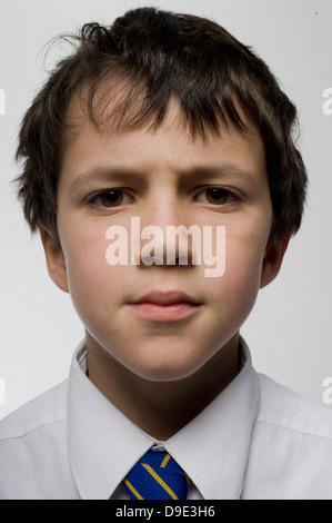 Giovane ragazzo che è curioso riflessivo e premuroso sette o otto anni, guardando direttamente in Lens Studio Foto Stock