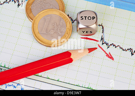 Tendenza ribassista grafico finanziario, matita rossa, freccia rossa, cubetti cubo con la parola STOP e delle monete da un euro. Messa a fuoco selettiva Foto Stock