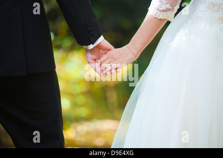 I giovani coniugi tenendo le mani sul giorno di nozze Foto Stock