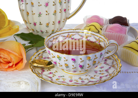 Antica coppa piena di tè con dolci di piccole dimensioni e in background isolato su bianco. Foto Stock