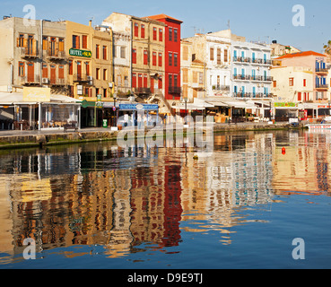 Alberghi e ristoranti nella pittoresca città vecchia di Chania si riflettono nell'acqua lungo il lungomare del Porto Veneziano Foto Stock