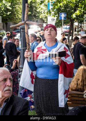 Donna che indossa bandiera georgiana prega in segno di protesta contro la manifestazione per la Giornata Internazionale contro l'Omofobia a Tbilisi. Foto Stock