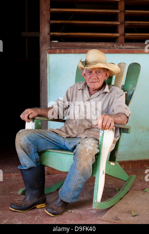 Coltivatore di tabacco indossando cappello di paglia su una sedia a dondolo fuori di casa sua, Vinales, Pinar Del Rio, Cuba, West Indies Foto Stock