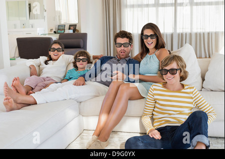 Famiglia di guardare la televisione a casa indossando occhiali 3D Foto Stock