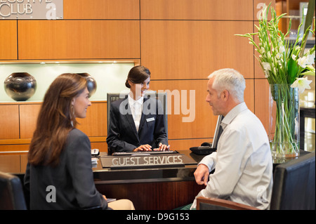 Azienda giovane parlando in un hotel e banco di ricevimento Foto Stock