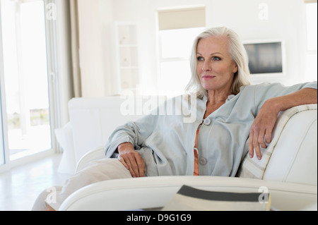 Donna seduta su un divano e di pensiero Foto Stock