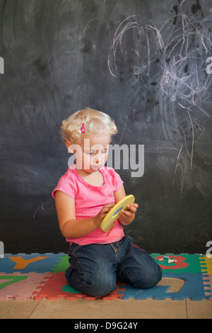 Ragazza che gioca con il numero puzzle nella parte anteriore di un bordo nero Foto Stock