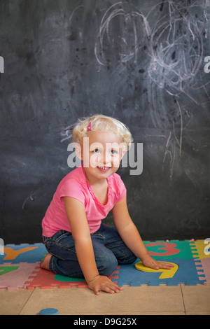 Ragazza che gioca con il numero puzzle nella parte anteriore di un bordo nero Foto Stock