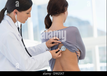 Medico donna esaminando una donna di ritorno con uno stetoscopio Foto Stock
