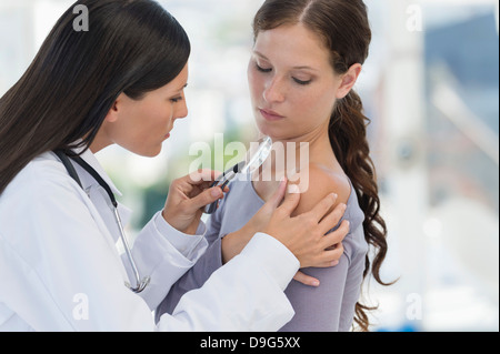 Il dermatologo con lente di ingrandimento per esaminare la donna di pelle Foto Stock