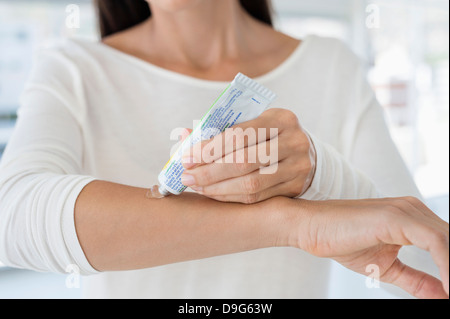 Donna applicazione di unguento sulla sua mano Foto Stock