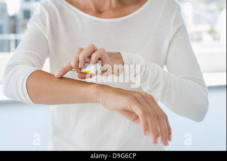 Donna applicazione di unguento sulla sua mano Foto Stock