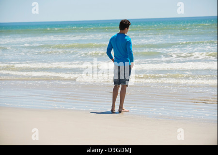 Uomo in piedi sulla spiaggia e guardando il mare Foto Stock