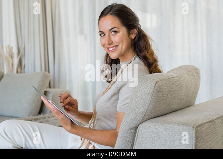 Bella donna utilizzando una tavoletta digitale e sorridente su un lettino Foto Stock