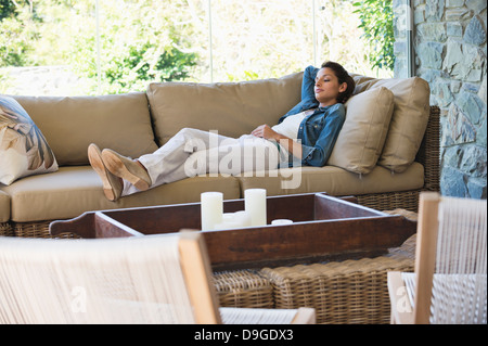 Donna sdraiata su un lettino in una stanza vivente Foto Stock