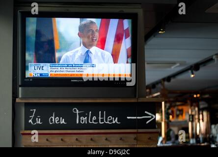 Berlino, Germania. 19 giugno 2013. Il Presidente Usa Barack Obama il discorso davanti la porta di Brandeburgo è visto dal vivo su uno schermo televisivo accanto ad una lettura del segno "bagni" presso una casa legata a Berlino, Germania, 19 giugno 2013. Foto: Julian Stratenschulte/dpa/Alamy Live News/dpa/Alamy Live News Foto Stock